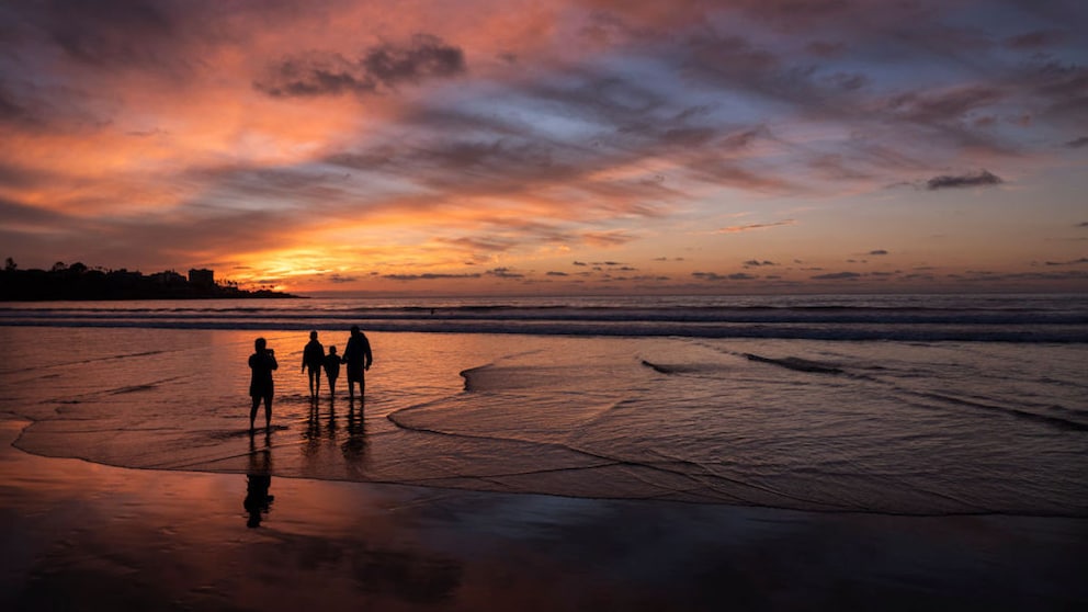 Familie mit Kindern am Strand bei Sonnenuntergang