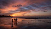 Familie mit Kindern am Strand bei Sonnenuntergang