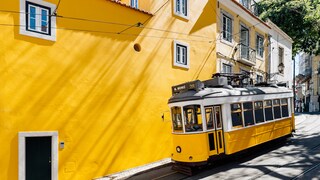 Gelbe Tram vor gelber Wand: Wir zeigen die besten Reisetipps für einen Trip nach Lissabon