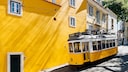 Gelbe Tram vor gelber Wand: Wir zeigen die besten Reisetipps für einen Trip nach Lissabon