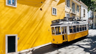 Gelbe Tram vor gelber Wand: Wir zeigen die besten Reisetipps für einen Trip nach Lissabon