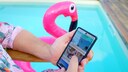 TRAVELBOOK im TV: Mann sitzt am Pool und hält Smartphone, auf dem Website zu sehen ist