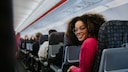 Frau mit mehr Beinfreiheit auf Standard-Sitzen im Flugzeug