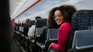 Frau mit mehr Beinfreiheit auf Standard-Sitzen im Flugzeug