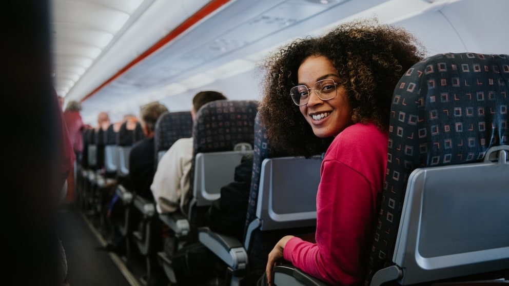 Frau mit mehr Beinfreiheit auf Standard-Sitzen im Flugzeug