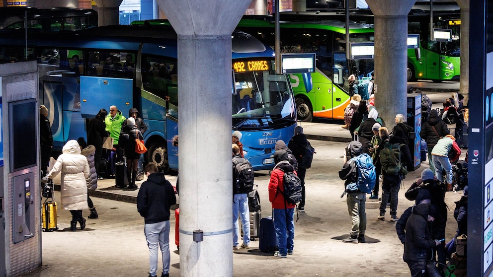 Reisende stehen vor den Fernbussen verschiedener Anbieter