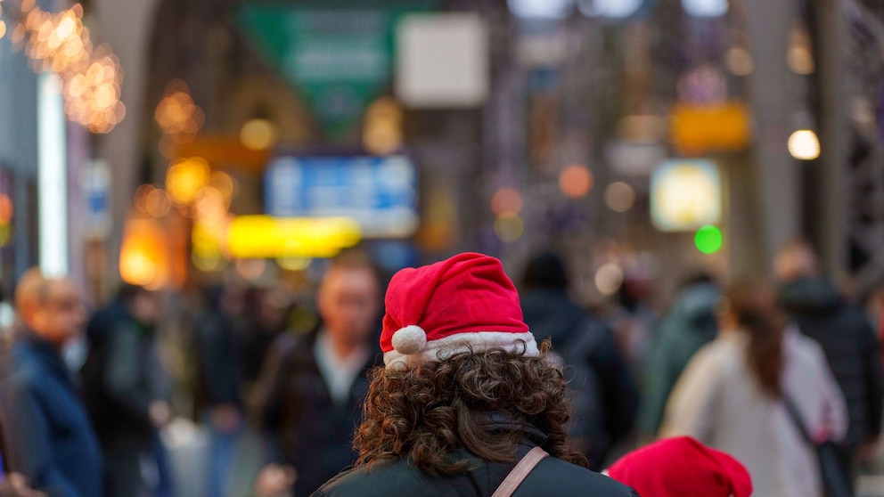 Eine Frau steht mit Weihnachtsmütze auf einem Bahnhof