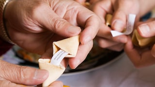 Hände öffnen einen Glückskeks: Er gehört für viele zum Besuch in einem chinesischen Restaurant – dabei liegt der Ursprung des Gebäcks eigentlich woanders