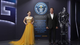 Emilia Clarke und Arnold Schwarzenegger posieren während der Seouler Premiere von „Terminator Genisys“ vor dem Schild, das auf einen Eintrag im Guinness-Buch der Rekorde für die größte Kinoleinwand der Welt hinweist