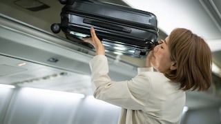 Frau verstaut kostenlos mitgeführtes Handgepäck