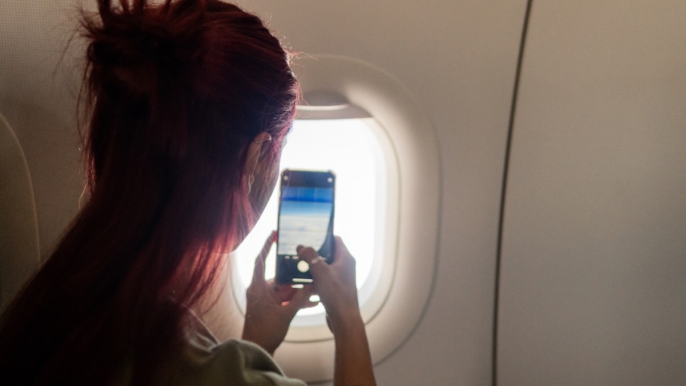 Frau beim Filmen im Flugzeug