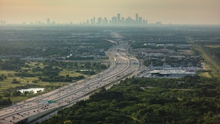 Blick auf einen Teil des Katy Freeways – die Straße gilt als breiteste Autobahn der Welt. Im Hintergrund ist die Skyline von Houston zu sehen.